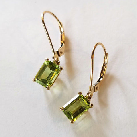 Yellow gold dangle earrings custom made with shimmering emerald cut peridot stones.