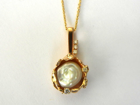 Custom design 14k yellow gold pendant with a pearl nestled in the centre and diamonds accenting the edges.