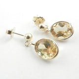Oval Citrines bezel set in 14 kt yellow gold and dangling from gold ball posts.
