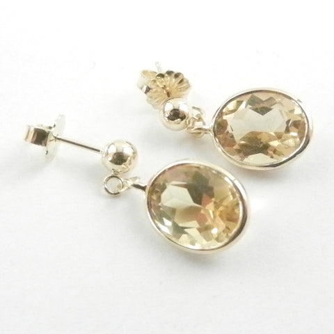 Oval Citrines bezel set in 14 kt yellow gold and dangling from gold ball posts.