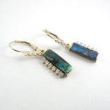 Rectangular black opal dangle earrings with diamonds along one side of each stone. Diamonds accent the leverbacks. Set in 14kt yellow gold. 