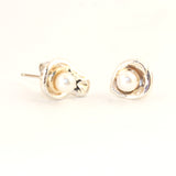 Custom design pearl earrings with silver and gold surrounding a luminous white pearl like a moon.